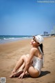 A woman in a white bathing suit sitting on the beach.