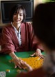 A woman sitting at a table playing a game of mahjong.