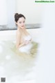 A woman sitting in a bathtub filled with foam.