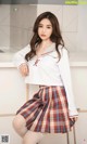 a woman in a white shirt and plaid skirt posing for a picture