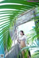 A woman in a bikini standing in front of a wooden door.