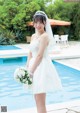 A woman in a wedding dress standing by a swimming pool.