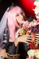 A woman with pink hair holding a bouquet of flowers.