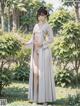 A woman in a white kimono standing in a garden.