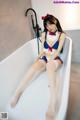 A woman in a sailor outfit sitting in a bathtub.