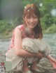 A woman sitting on the ground in front of a river.