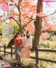 A group of women sitting on a wooden fence in front of a tree.