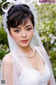 A woman in a wedding dress with a veil and pearls.