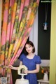 A woman standing in front of a window holding a vase of flowers.