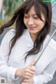 A woman in a white shirt holding an umbrella.