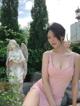 A woman in a pink dress posing in front of a statue.