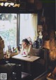 A woman sitting at a table in front of a window.