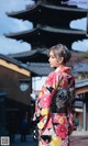 A woman in a kimono standing in front of a pagoda.