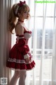 A woman in a red and white dress standing by a window.