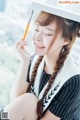 A woman in a graduation cap and gown holding a pencil.