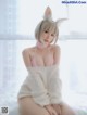 A woman in a bunny costume sitting on a bed.