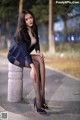 A woman sitting on top of a cement pillar.