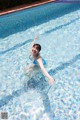 A woman in a blue bikini is swimming in a pool.