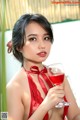 A woman in a red lingerie holding a glass of wine.