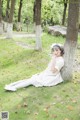 A woman in a white dress sitting under a tree.